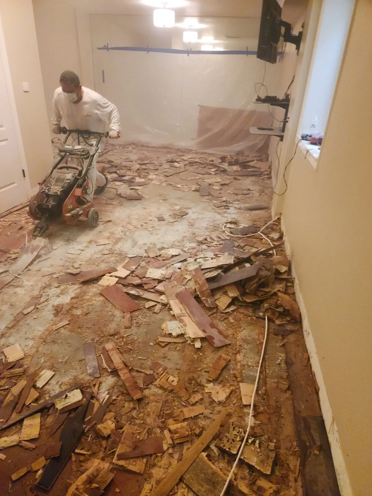 Crew member removing old wood flooring with a floor scraper