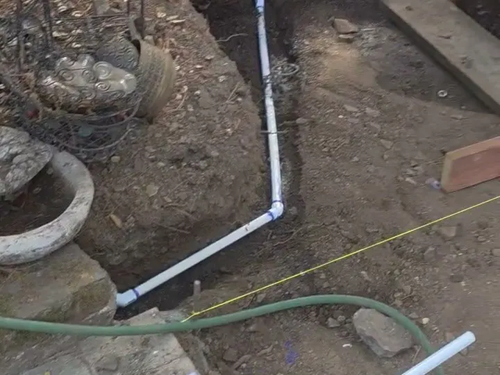 White drain pipe laid in a trench in the dirt before paving