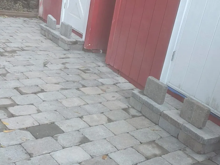 Paver patio beside a red shed with paver steps being built at the doors