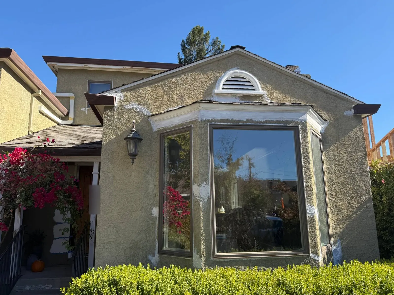 Stucco front of a Redwood City house with cracks and corners patched in white before painting