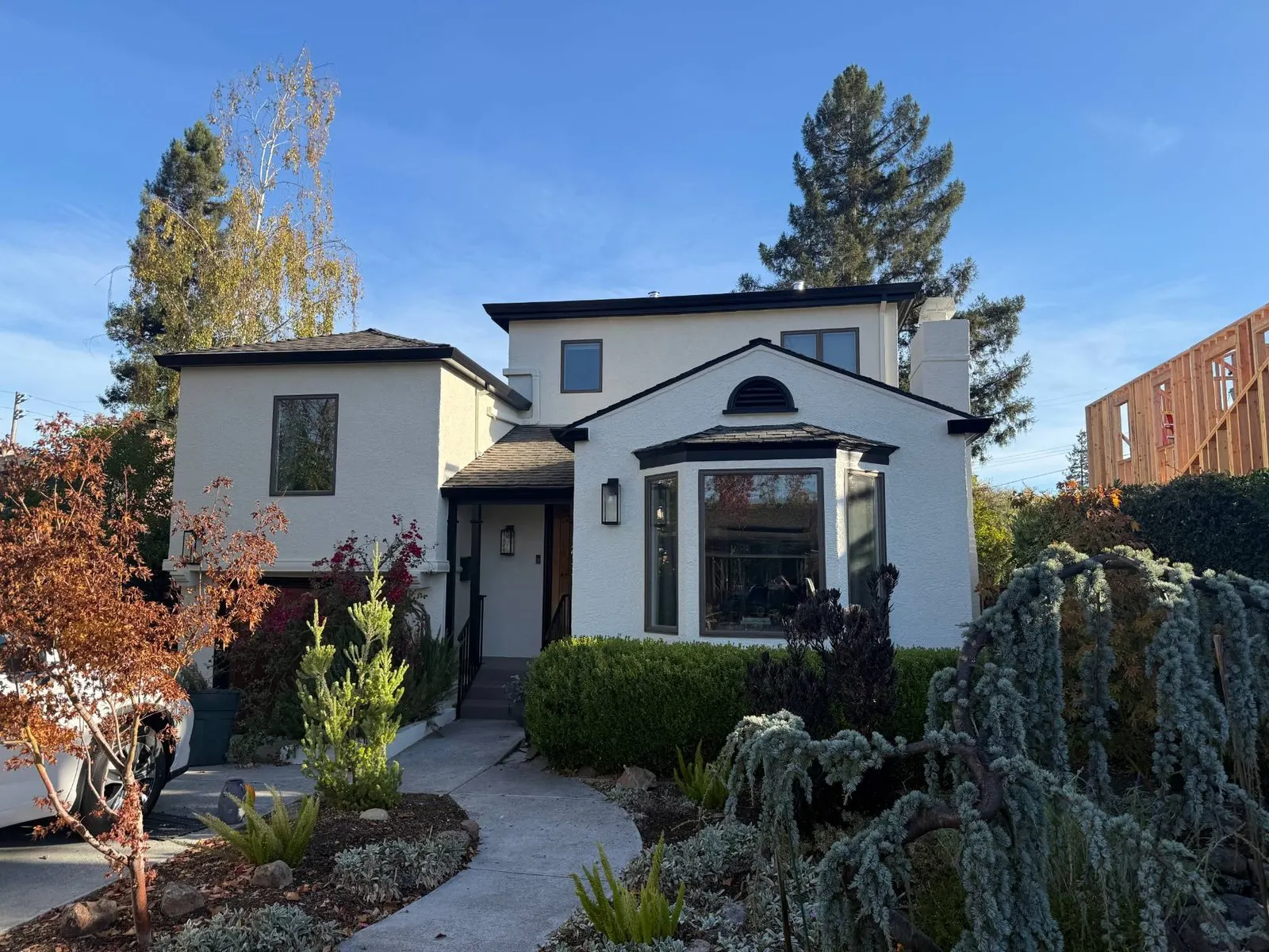 Two-story stucco house painted warm white with black trim